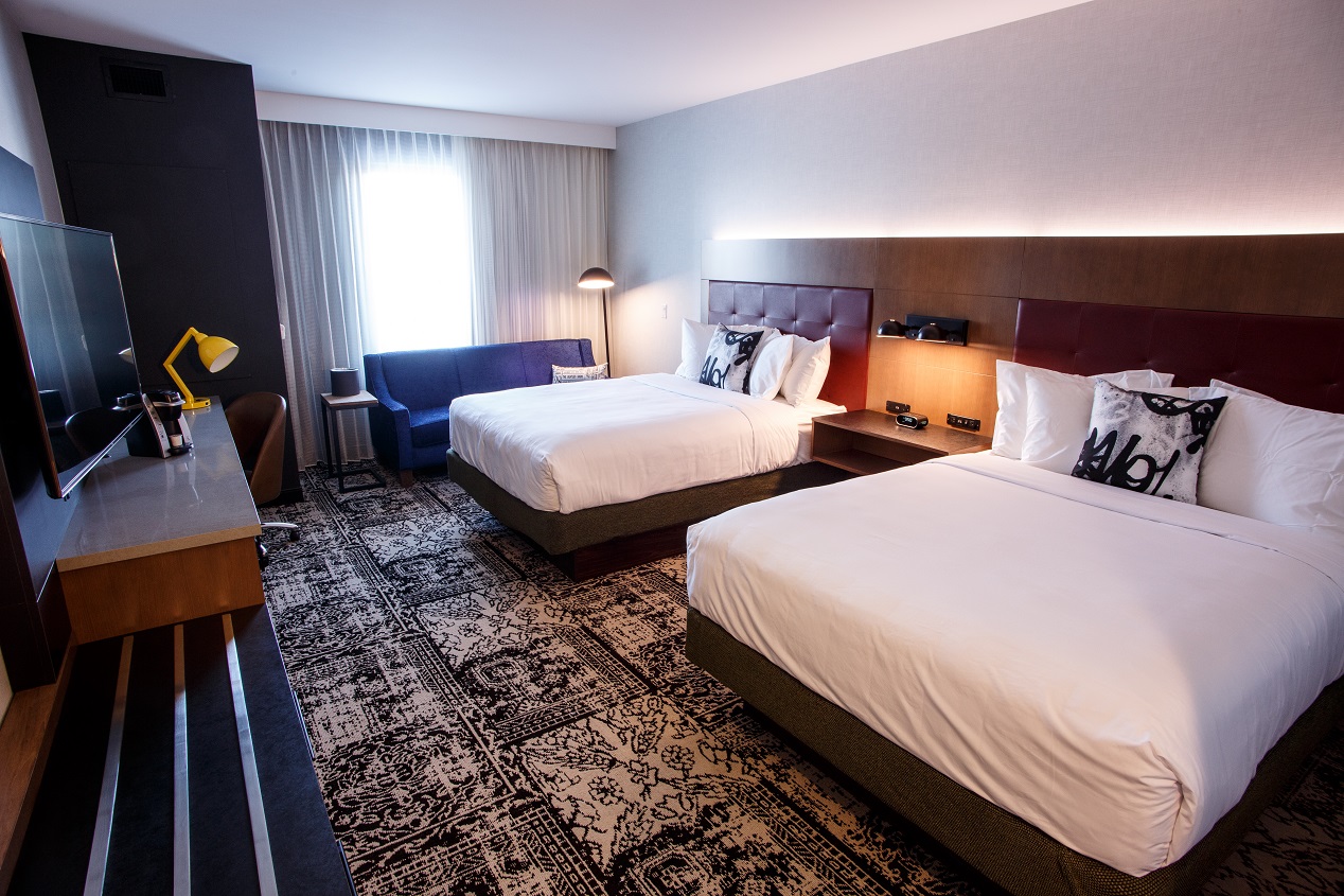 A double queen bedroom showing beds, beautiful blue couch and television